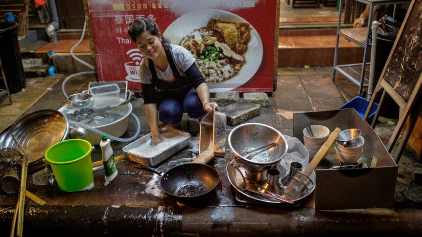 Stall-holder washes kitchenware in street
