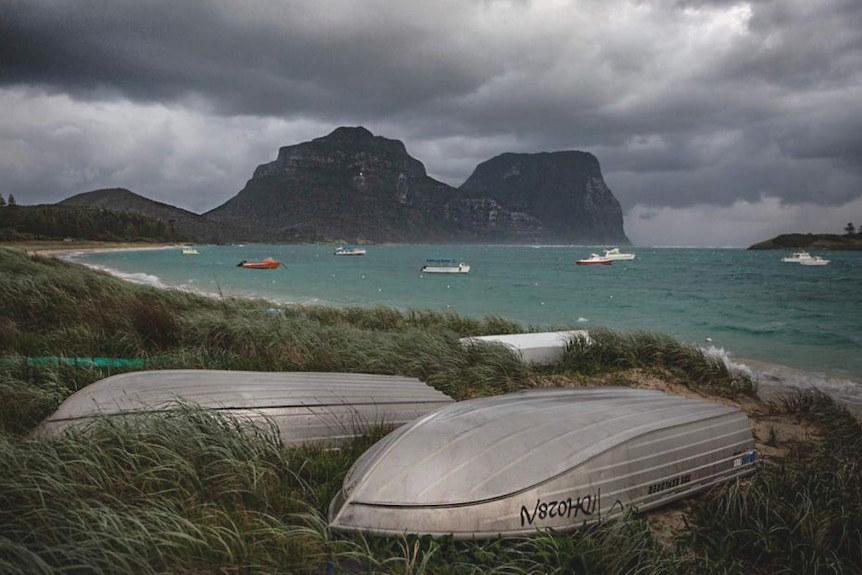 Several small metal boats on sand near a beach.