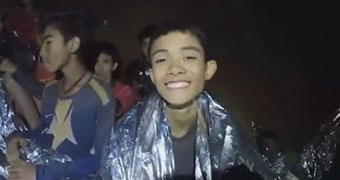 Boys wrapped in thermal blankets smiling for the camera