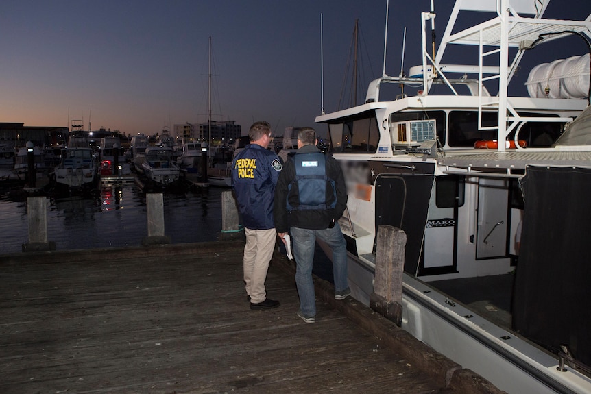 Police officers stand next to a boat.