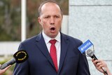 Immigration Minister Peter Dutton gestures and speaks to reporters at Parliament House.