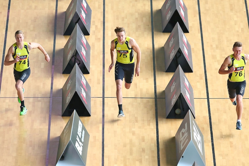 Three young Aussie rules players, including Harry Himmelberg (left), sprint down lanes in a gym during a fitness test.  