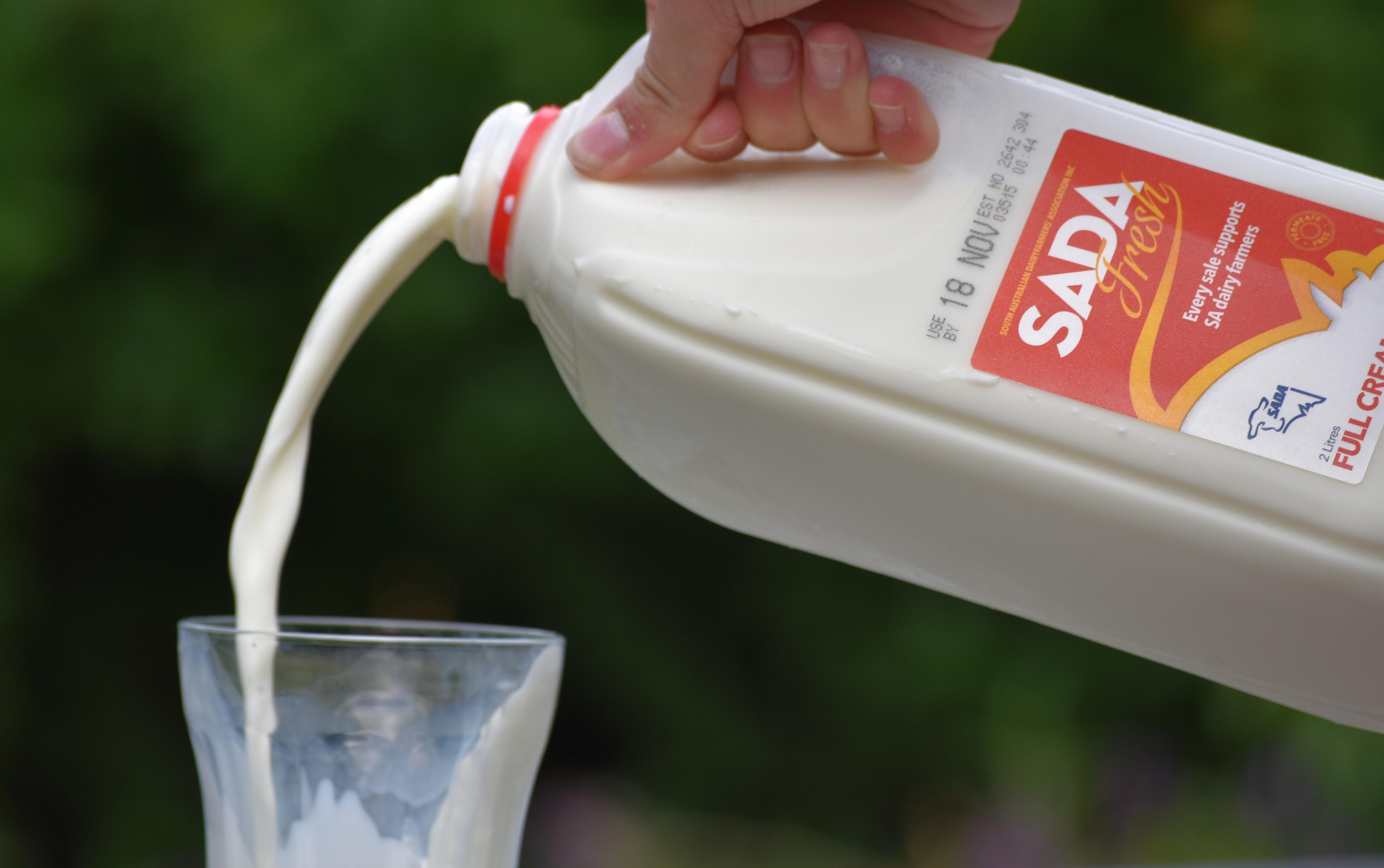 A two-litre bottle of SADA fresh milk being poured into a glass.