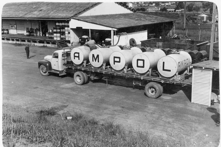 A truck with Ampol markings fills up at a depot in a black and white photo.