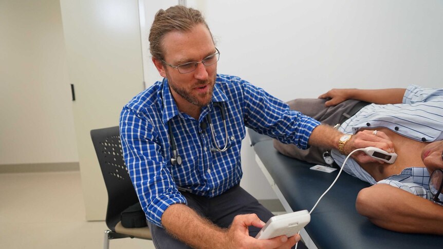 Dr Josh Francis using the hand-held echocardiography device on a patient.