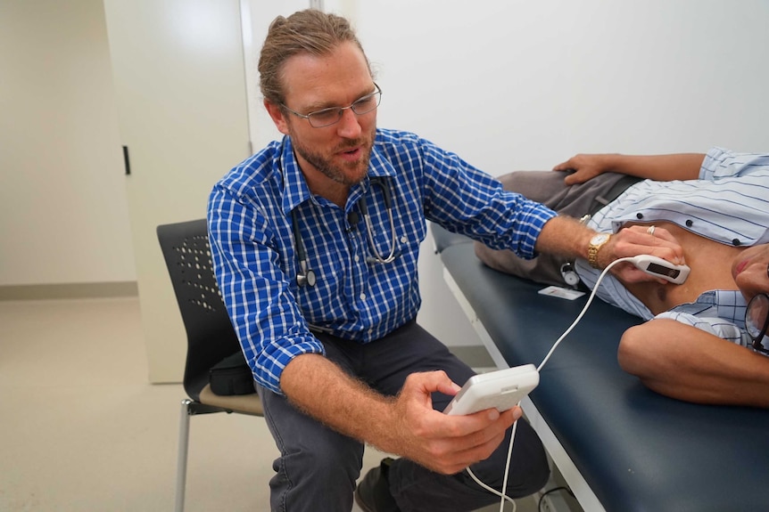 Dr Josh Francis using the hand-held echocardiography device on a patient.