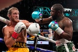 Logan P{aul backs away from Floyd Mayweather in a ring