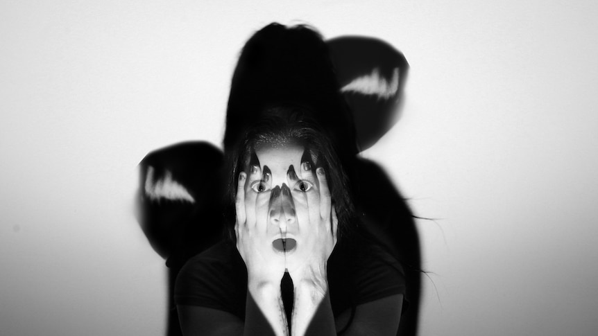 A black and white portrait of a young women covering her face.