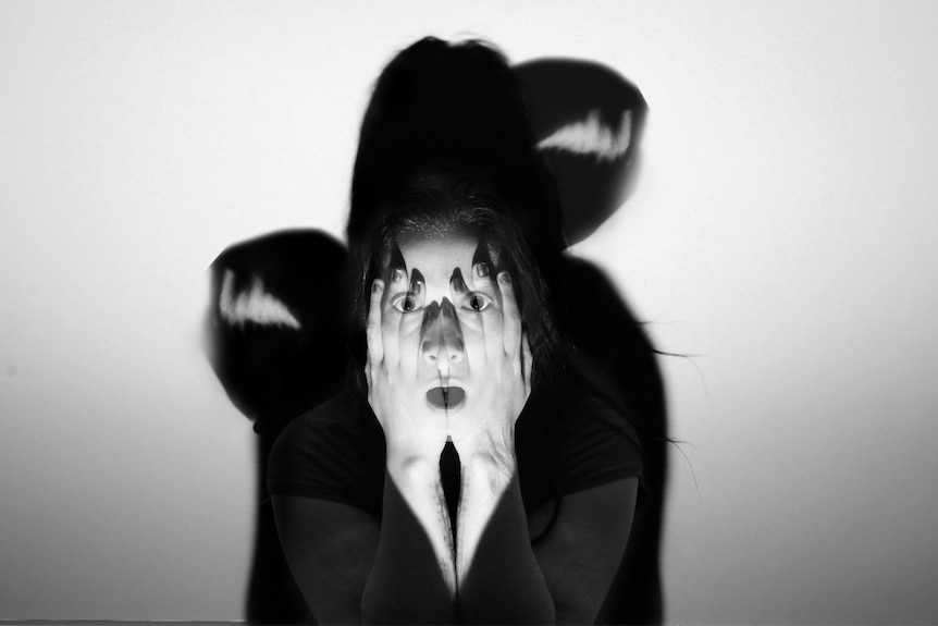 A black and white portrait of a young women covering her face.
