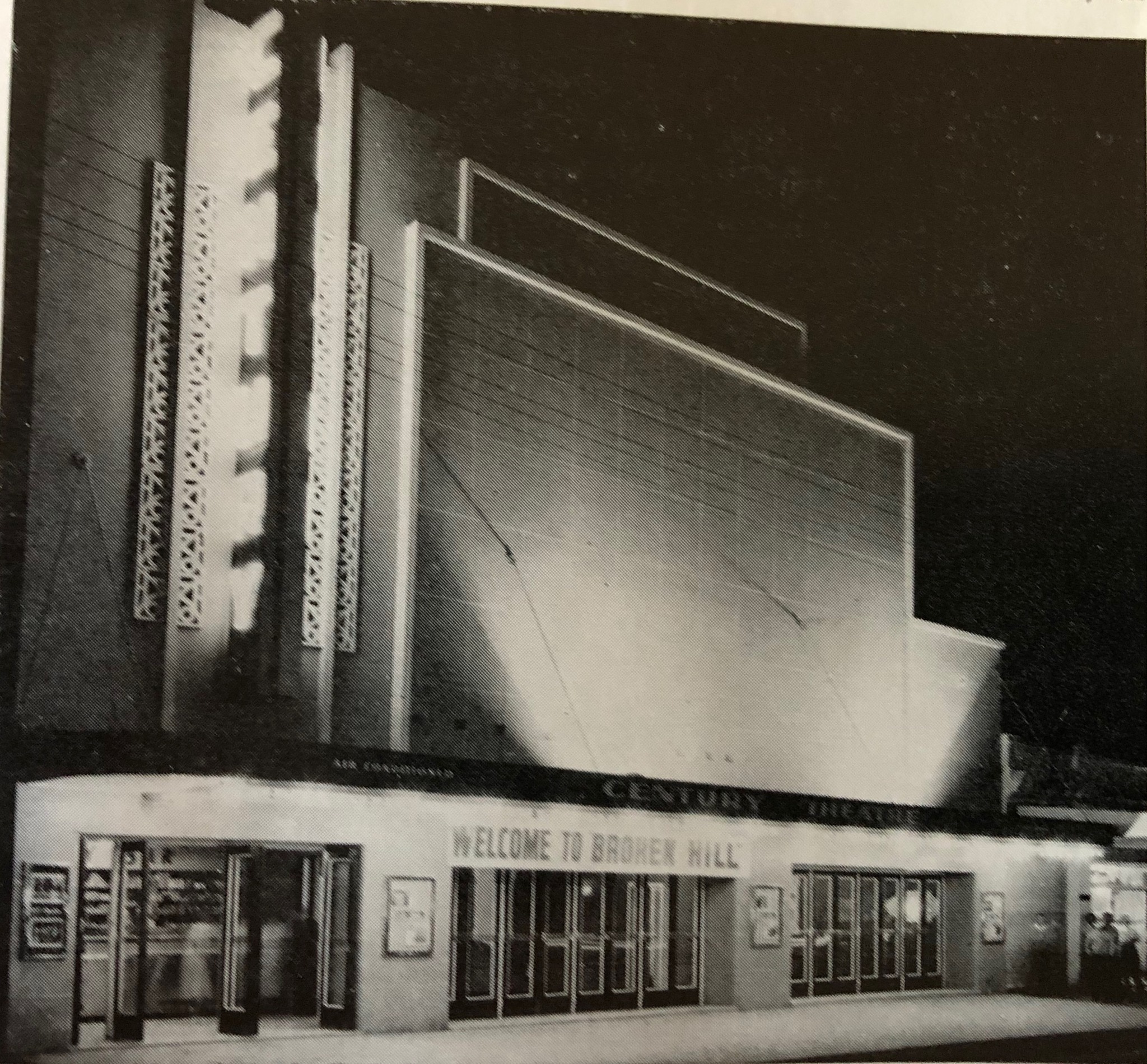 Una antigua fotografía en blanco y negro de un edificio Art Deco iluminado por luces brillantes 
