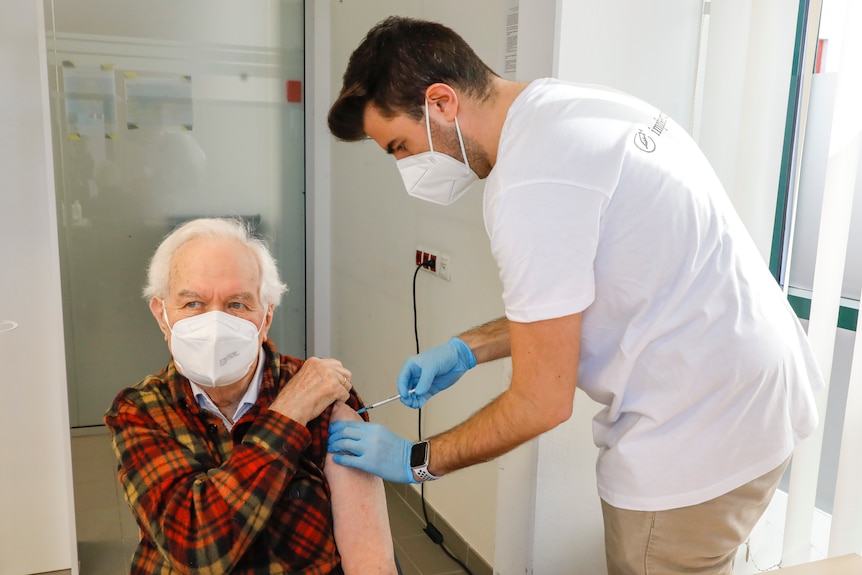A man wearing a mask gets a covid vaccine