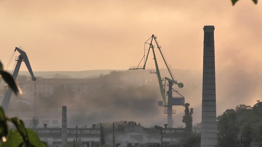 Smoke rises at a shipyard.
