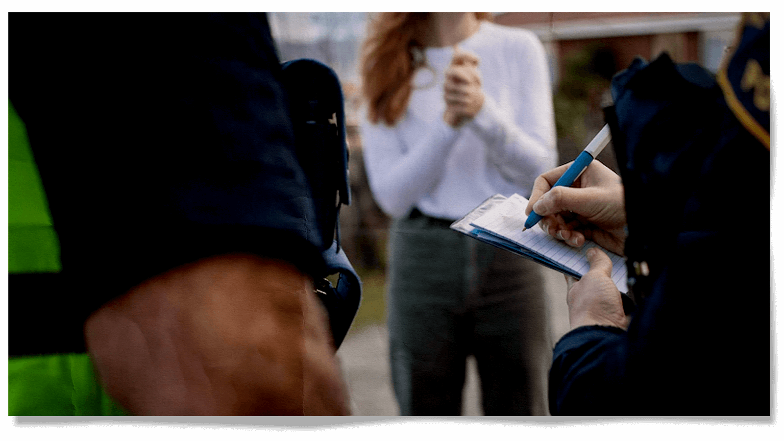 Two police officers with a notepad speak to an unidentifiable woman