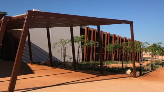 A front view of a government building with red dirt and blue skies
