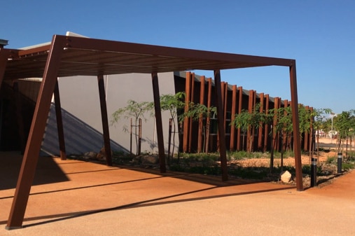 A front view of a government building with red dirt and blue skies