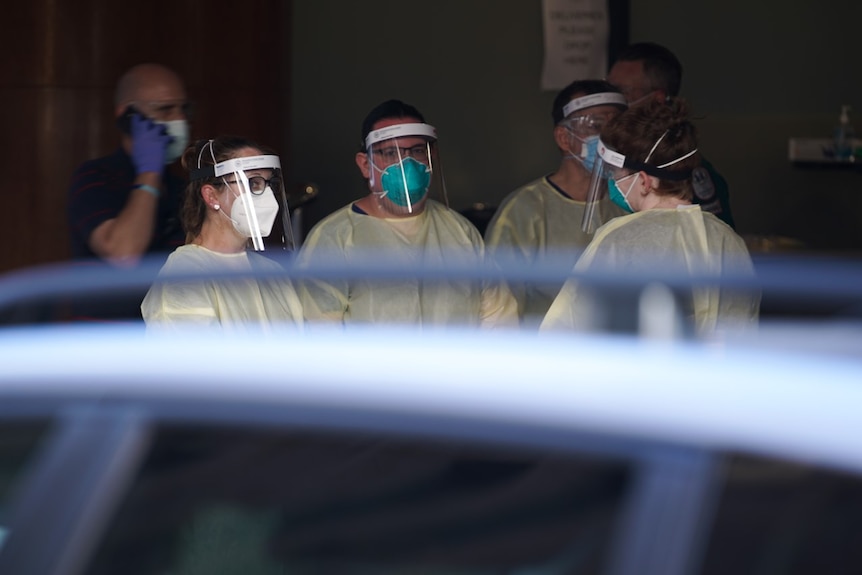 SA Health staff wearing full PPE stand in front of Peppers Waymouth Hotel