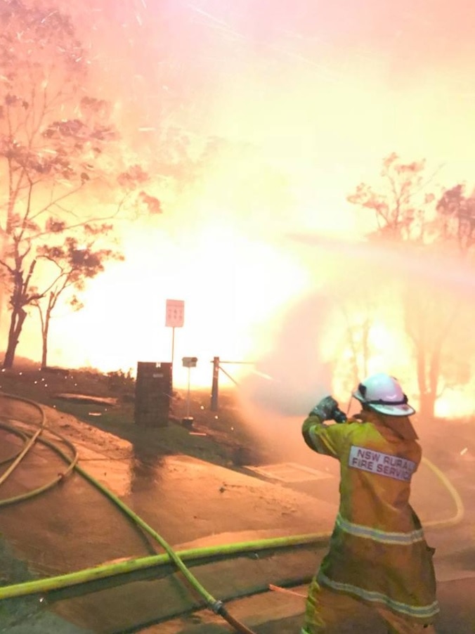 A man sprays water on a wall of fire.