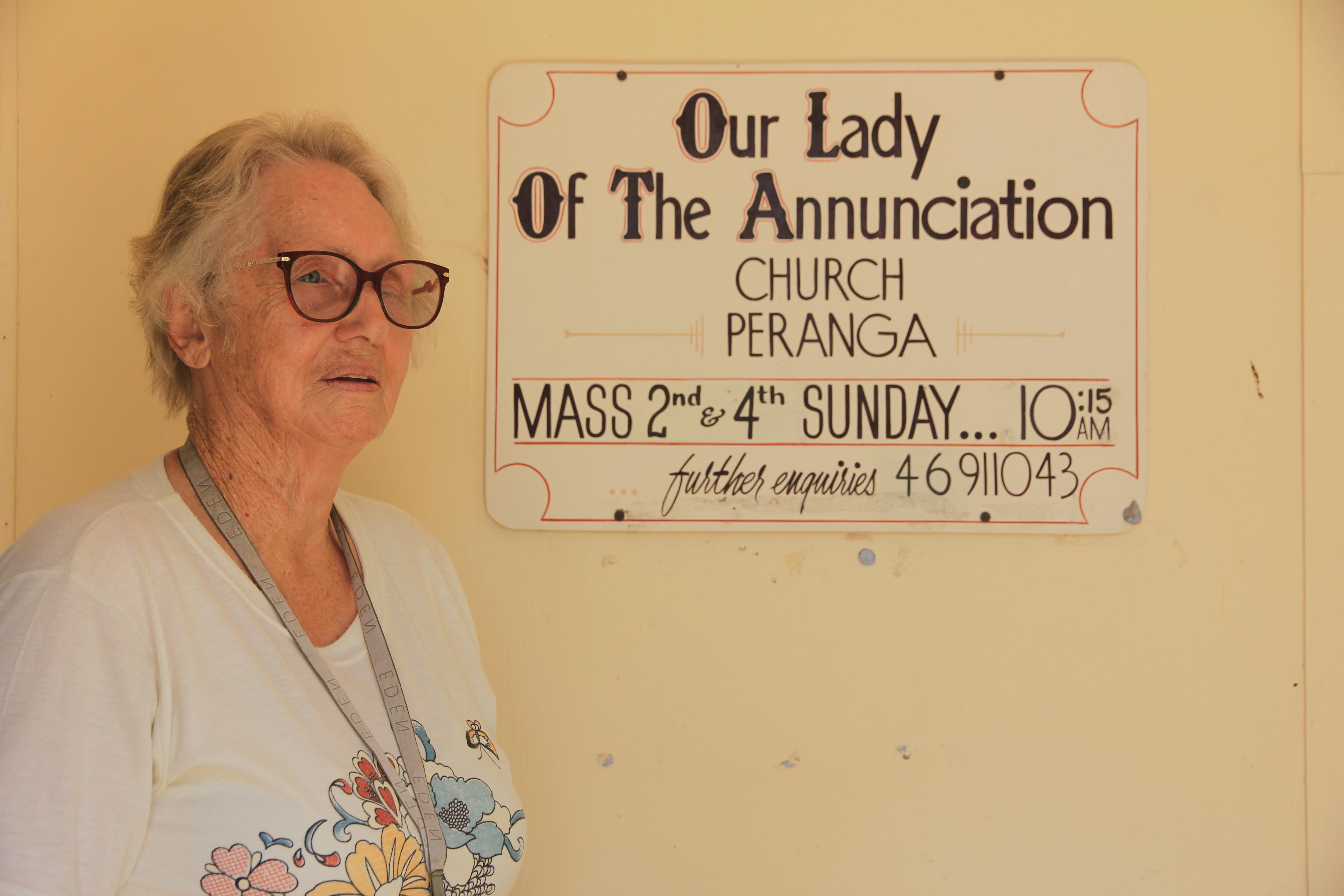 Мэри стоит рядом со старой церковной вывеской, рекламировавшей время проведения мессы.  