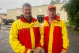 two men in surf life saving jackets smile at the camera