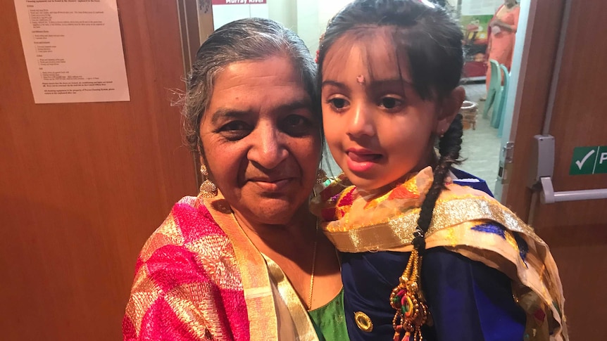 An elderly Indian woman holds a young girl.