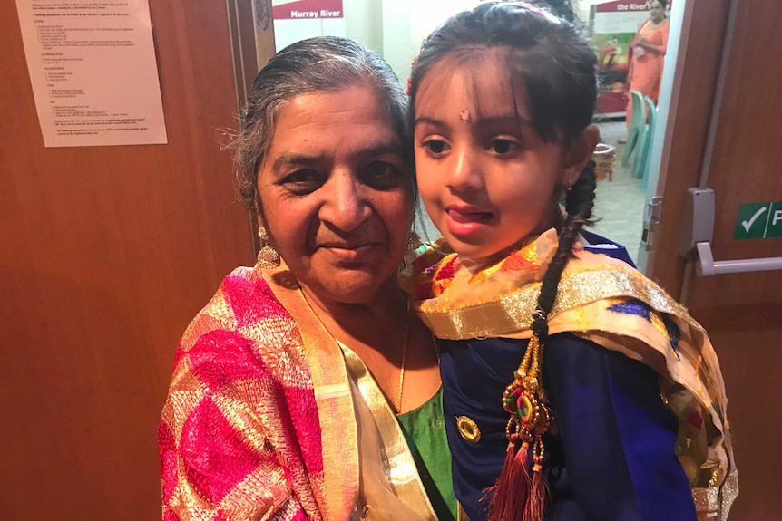 An elderly Indian woman holds a young girl.