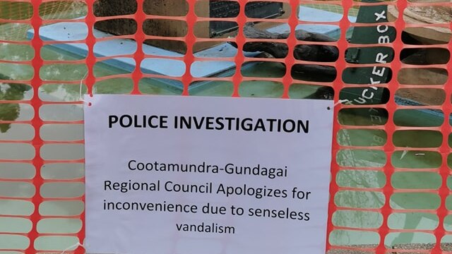 A temporary red mesh fence is erected around the toppled fountain mounted with a sign that says 'Police investigation'.