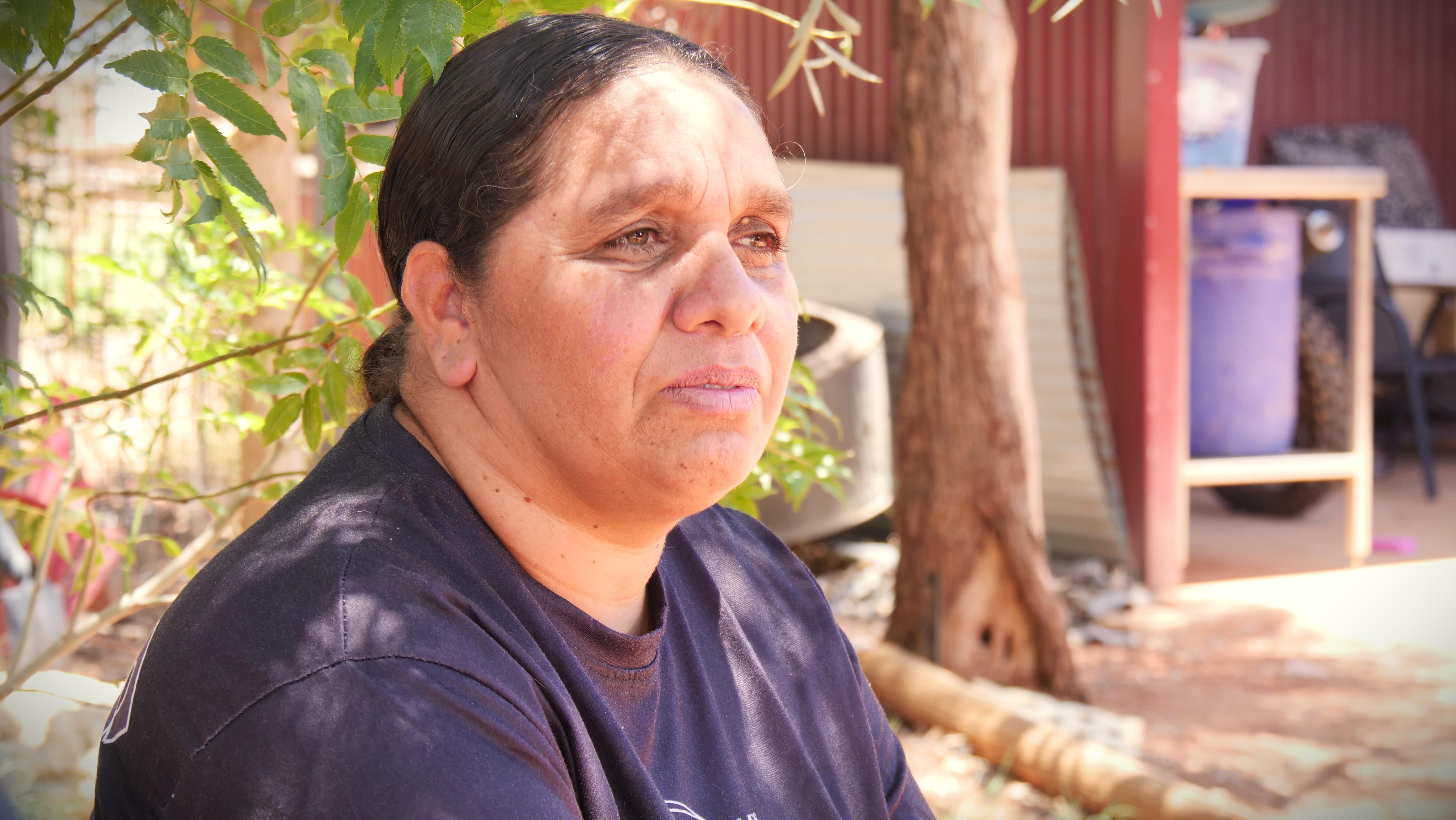A woman sits in the backyard of her home