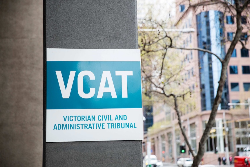 A blue and white sign stands on a concrete pillar.