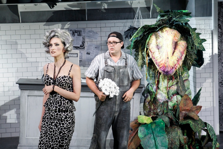 Production still showing Audrey and Seymour and carnivorous plant Audrey II in the background.