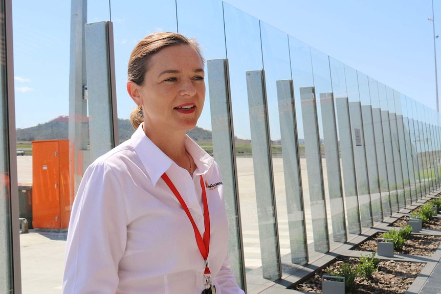 A women in the open air viewing area at an airport tarmac.