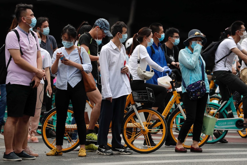 A group of people in face masks on a street corner in Beijing