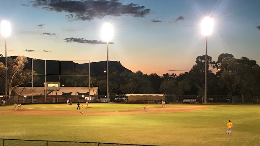 A desert baseball diamond where players play under lights.