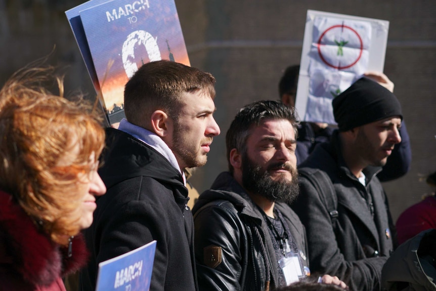 A group of people hold signs in a protest.