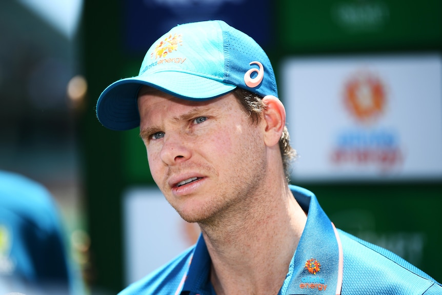 Steve Smith looks to one side wearing a green baseball cap