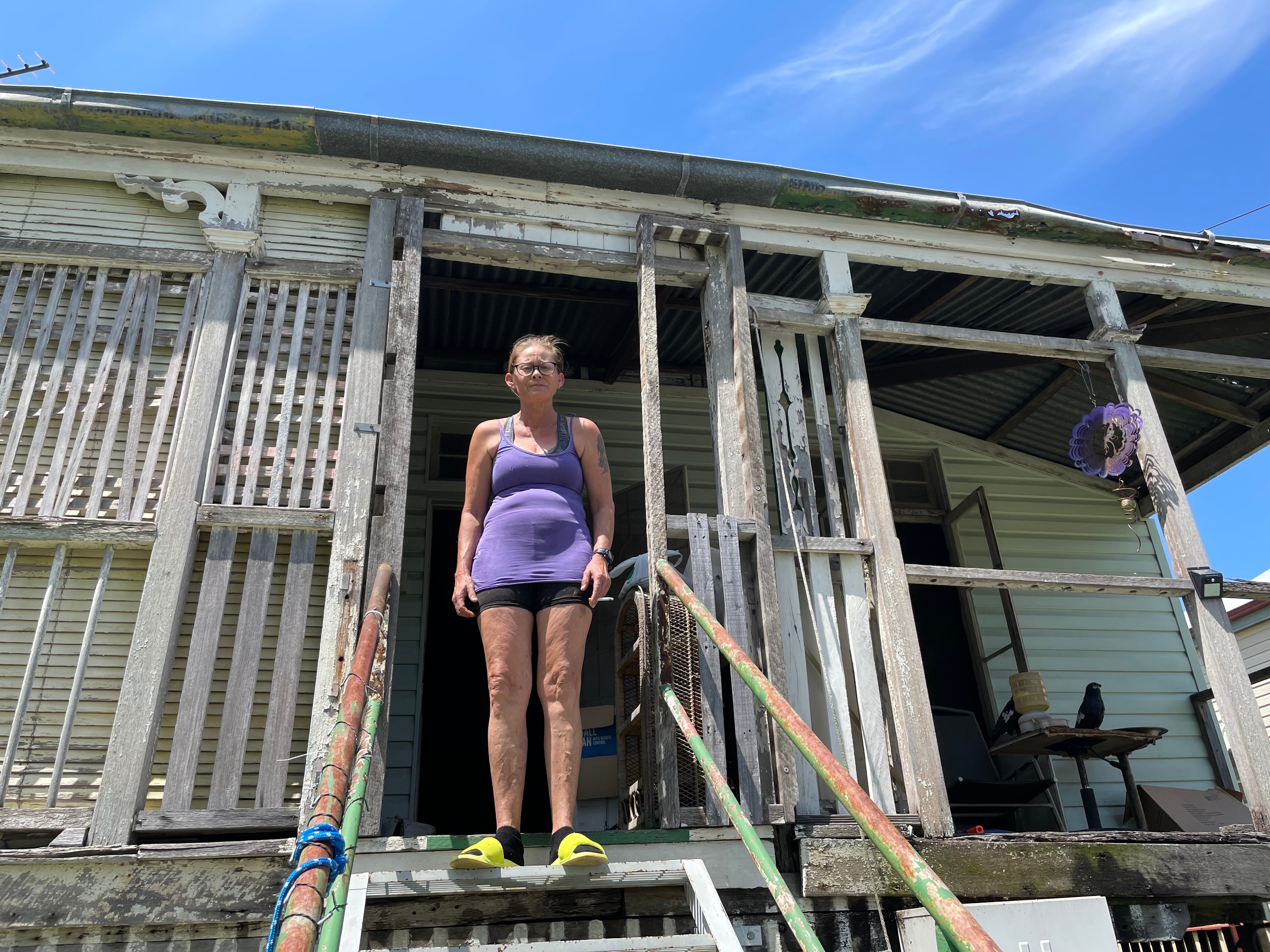 Midge Cohen stands in a doorway of her rundown high-set home.