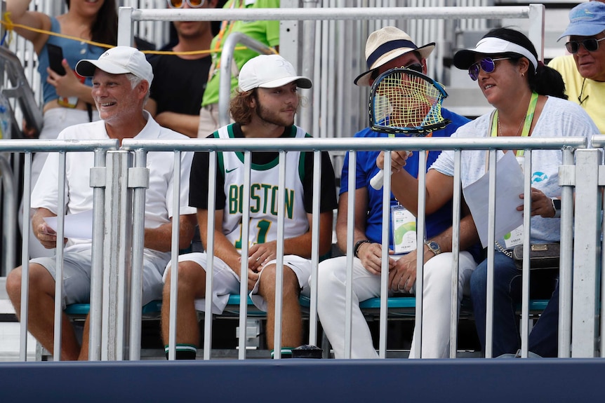 A spectator holds and looks at Nick Kyrgios's smashed racquet in the grandstand at the Miami Open.