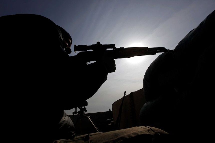 The silhouette of an Iraqi sniper from a low perspective looking up.
