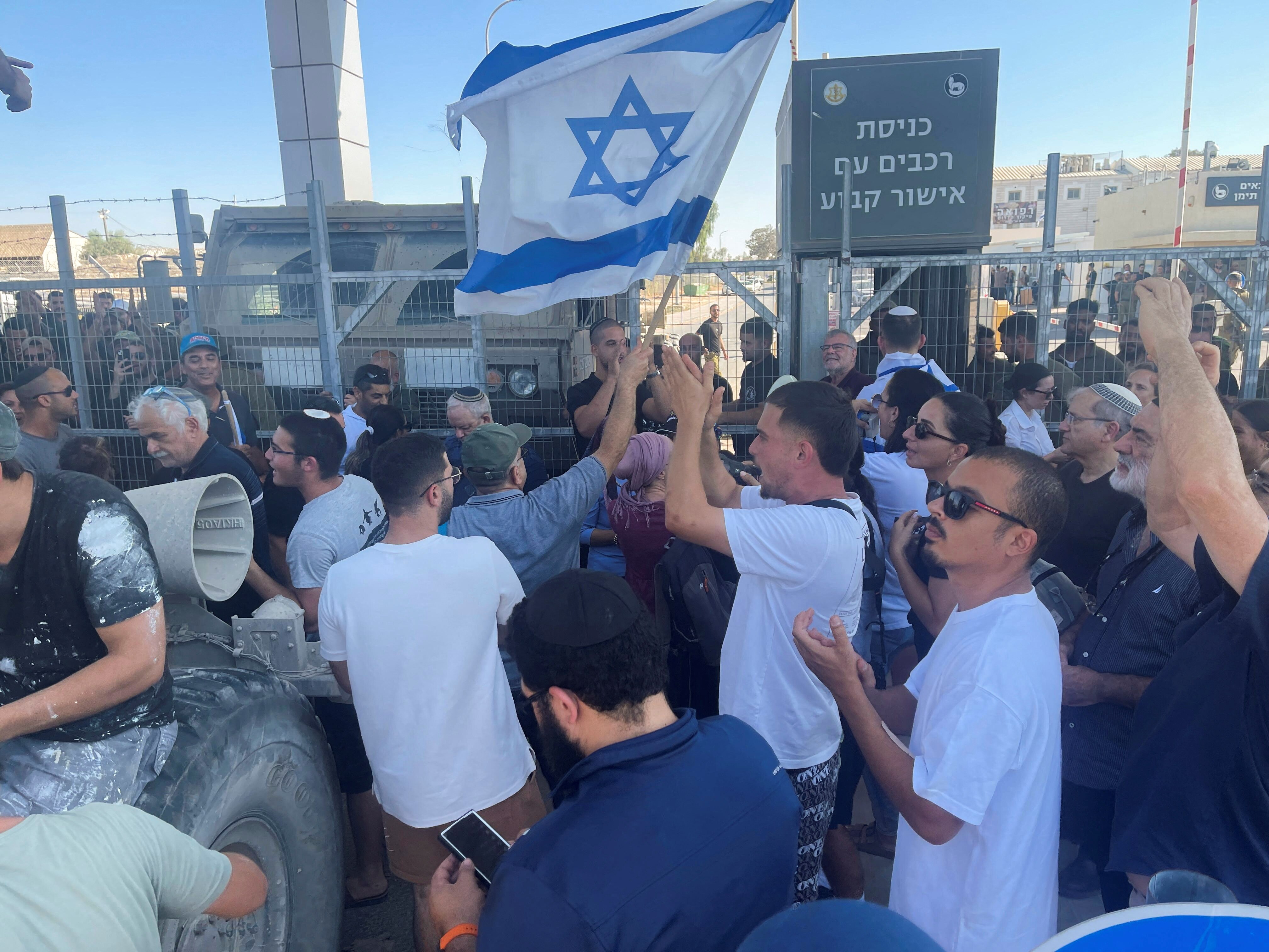 A group of people crowded near a fence carrying the israeli flag