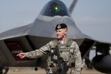 US soldier stands in front of F-22 stealth fighter