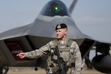 US soldier stands in front of F-22 stealth fighter