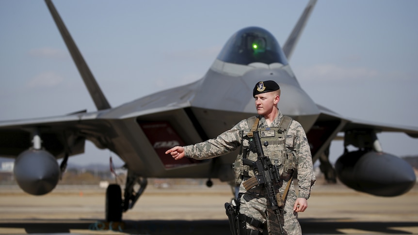 US soldier stands in front of F-22 stealth fighter