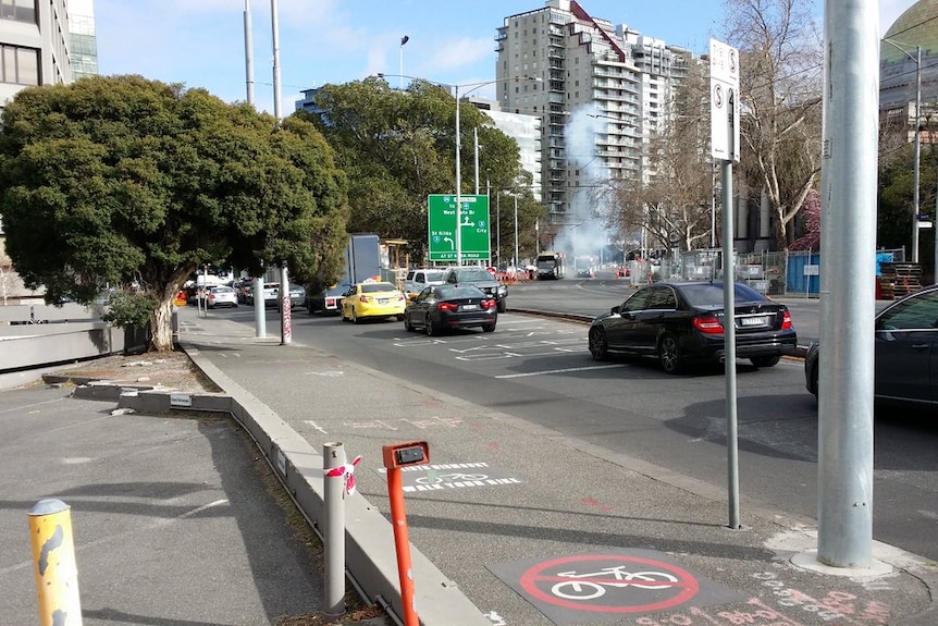 Smoke is seen coming from a tram after power lines come down on St Kilda Road.