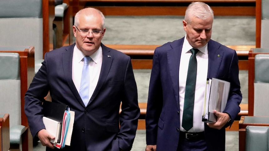 Two men in suits holding binders stride with purpose