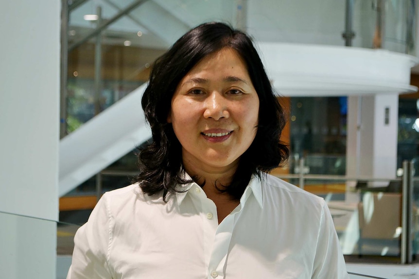 Woman in white shirt smiles.