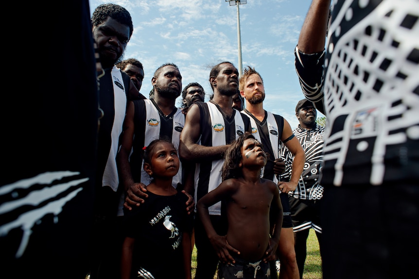 magpies players and fans listening to a coach