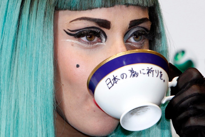 Lady Gaga, drinks from a teacup with the words 'Pray for Japan' written on it.