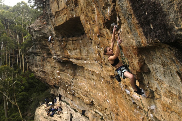 Libby Hall hangs off a rock high above the ground.