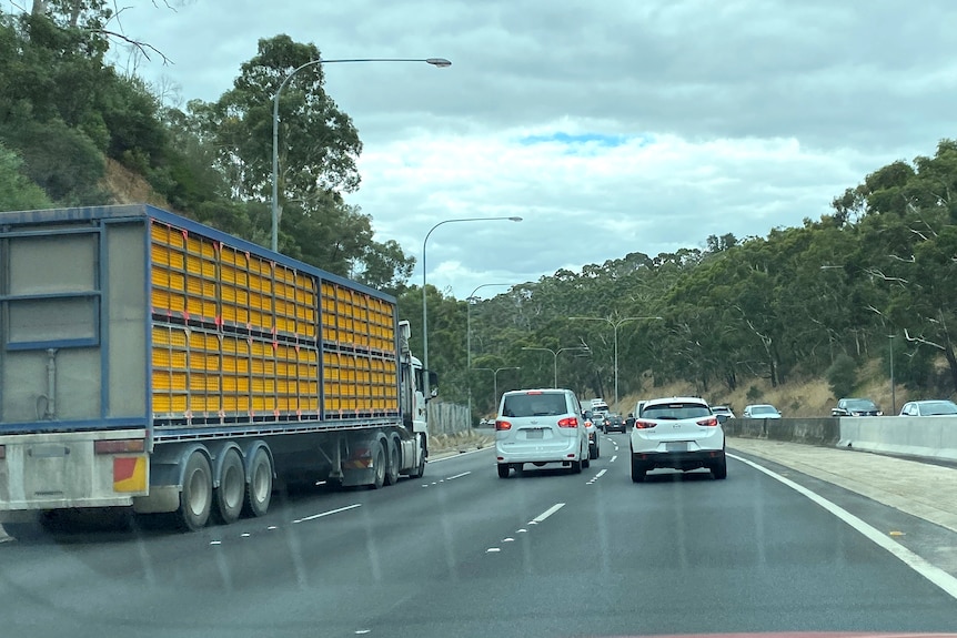 Cars and a truck occupy all lanes of a multi-lane highway surrounded by hills