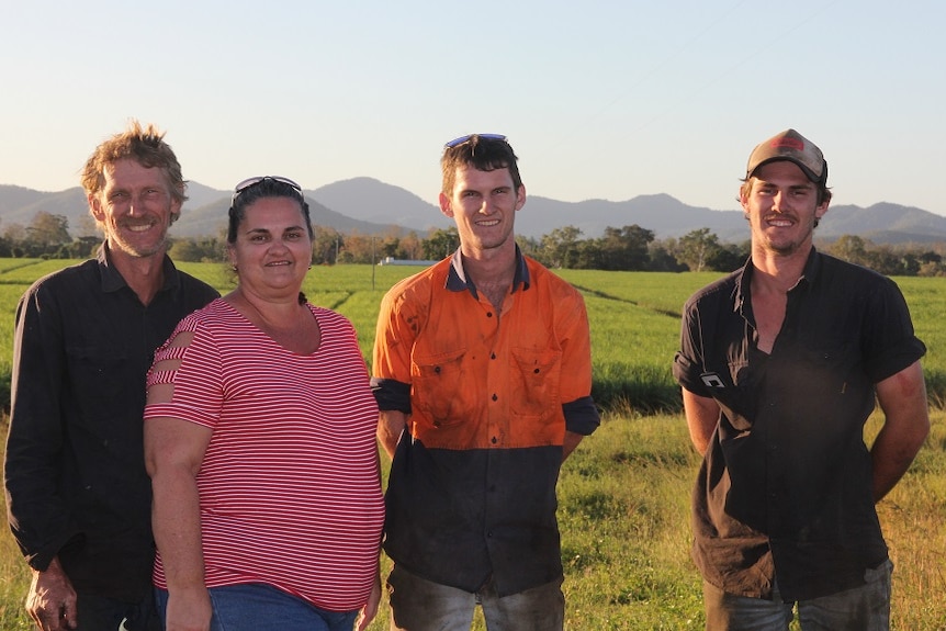 The Head family stands on top of a ridge with cane fields in the background.