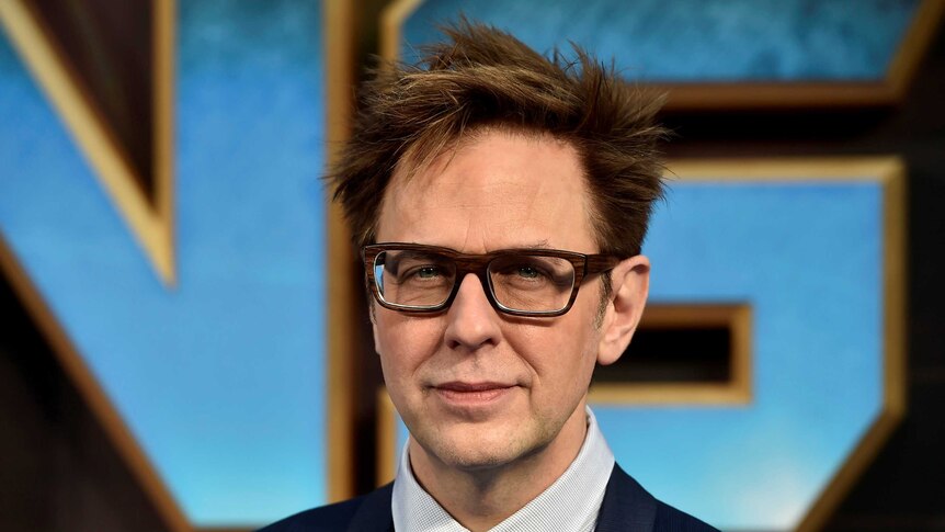 James Gunn, wearing a suit, poses for a photo.